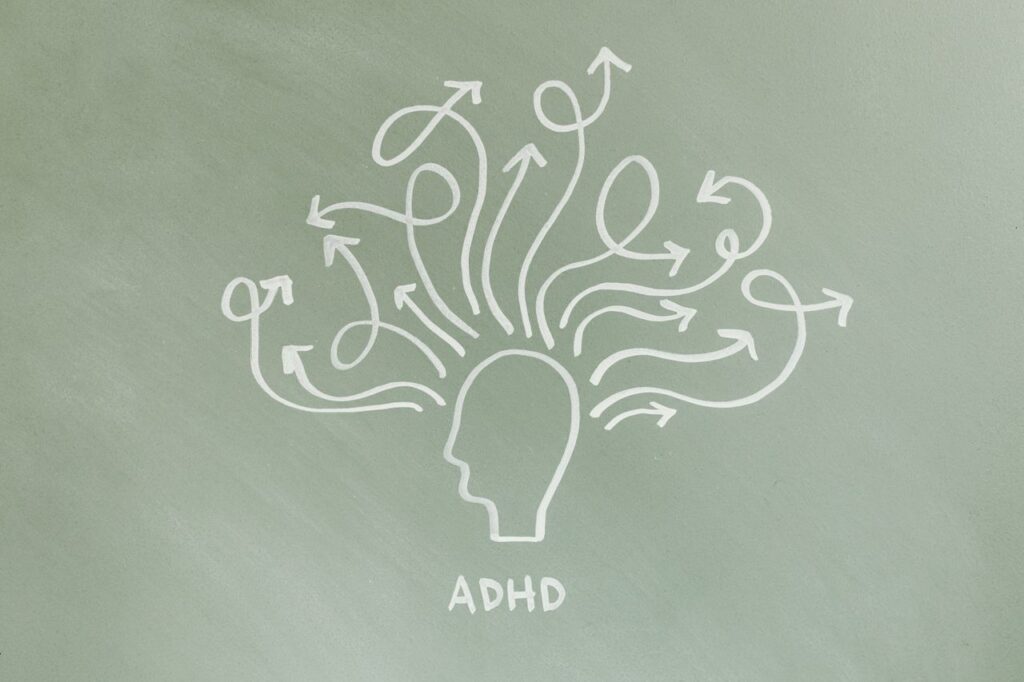 Osoba dorosła z ADHD podczas pracy przy biurku, rozproszona nad dokumentami i laptopem.